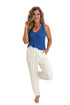 Front view of woman wearing Swagger Boutique’s White Woven Pants with blue tank against white studio background.