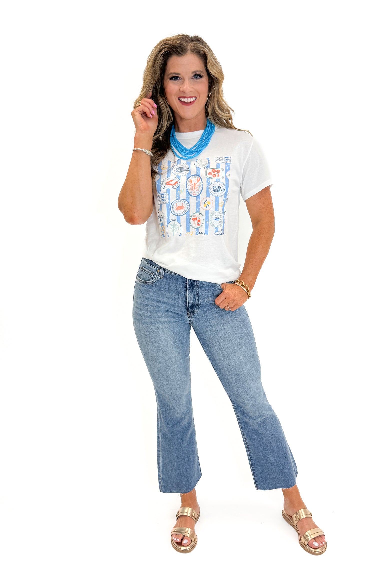 Front view of woman wearing Swagger Boutique’s White &amp; Blue Printed Graphic T-Shirt with jeans against white studio background.