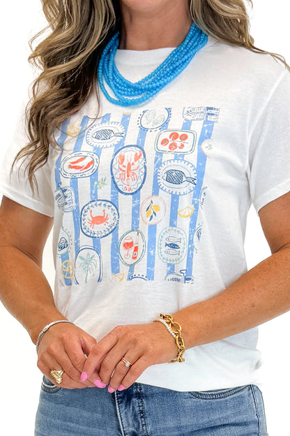 Front detail view of woman wearing Swagger Boutique’s White &amp; Blue Printed Graphic T-Shirt with jeans against white studio background.