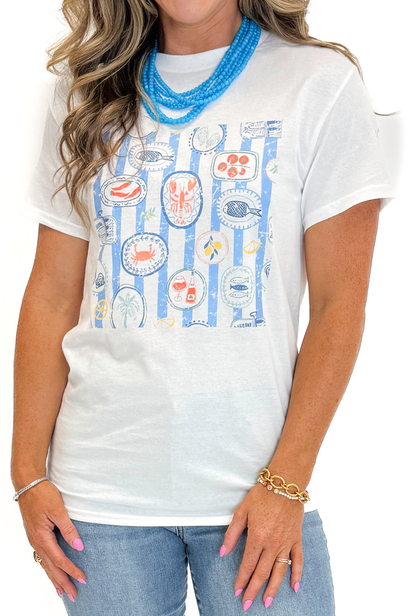 Front detail view of woman wearing Swagger Boutique’s White &amp; Blue Printed Graphic T-Shirt with jeans against white studio background.