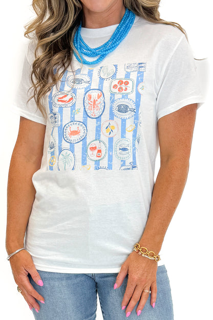 Front detail view of woman wearing Swagger Boutique’s White &amp; Blue Printed Graphic T-Shirt with jeans against white studio background.