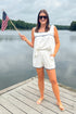 Front view of woman wearing Swagger Boutique’s White & Blue Square Neck Stitch Detail Tank with matching shorts standing on a dock at the lake.