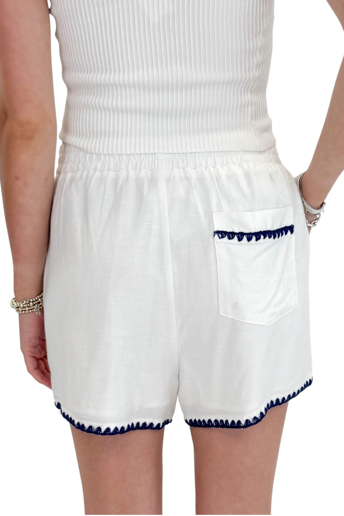 Back detail view of woman wearing Swagger Boutique’s White &amp; Blue Square Neck Stitch Detail Tank with Off White Ribbed Tube Top against white studio background.