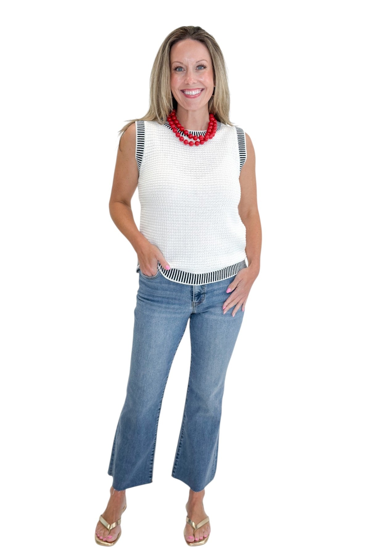 Front view of woman wearing Swagger Boutique’s White &amp; Navy Textured Sweater Tank with jeans against white studio background.