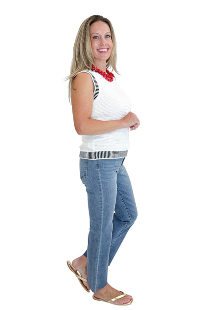 Side view of woman wearing Swagger Boutique’s White &amp; Navy Textured Sweater Tank with jeans against white studio background.