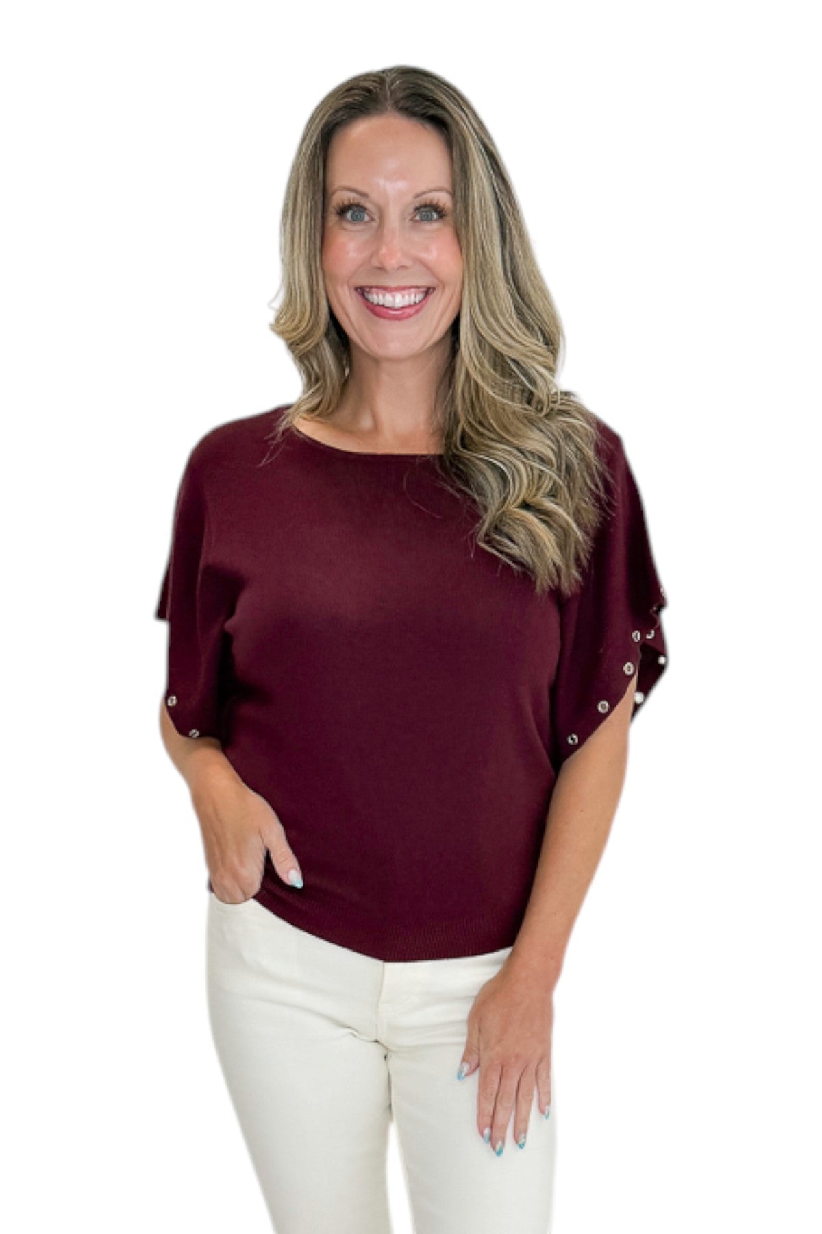 Front view of woman wearing Swagger Boutique’s Wine Grommet Sleeve Knit Top by Entro with jeans against white studio background.