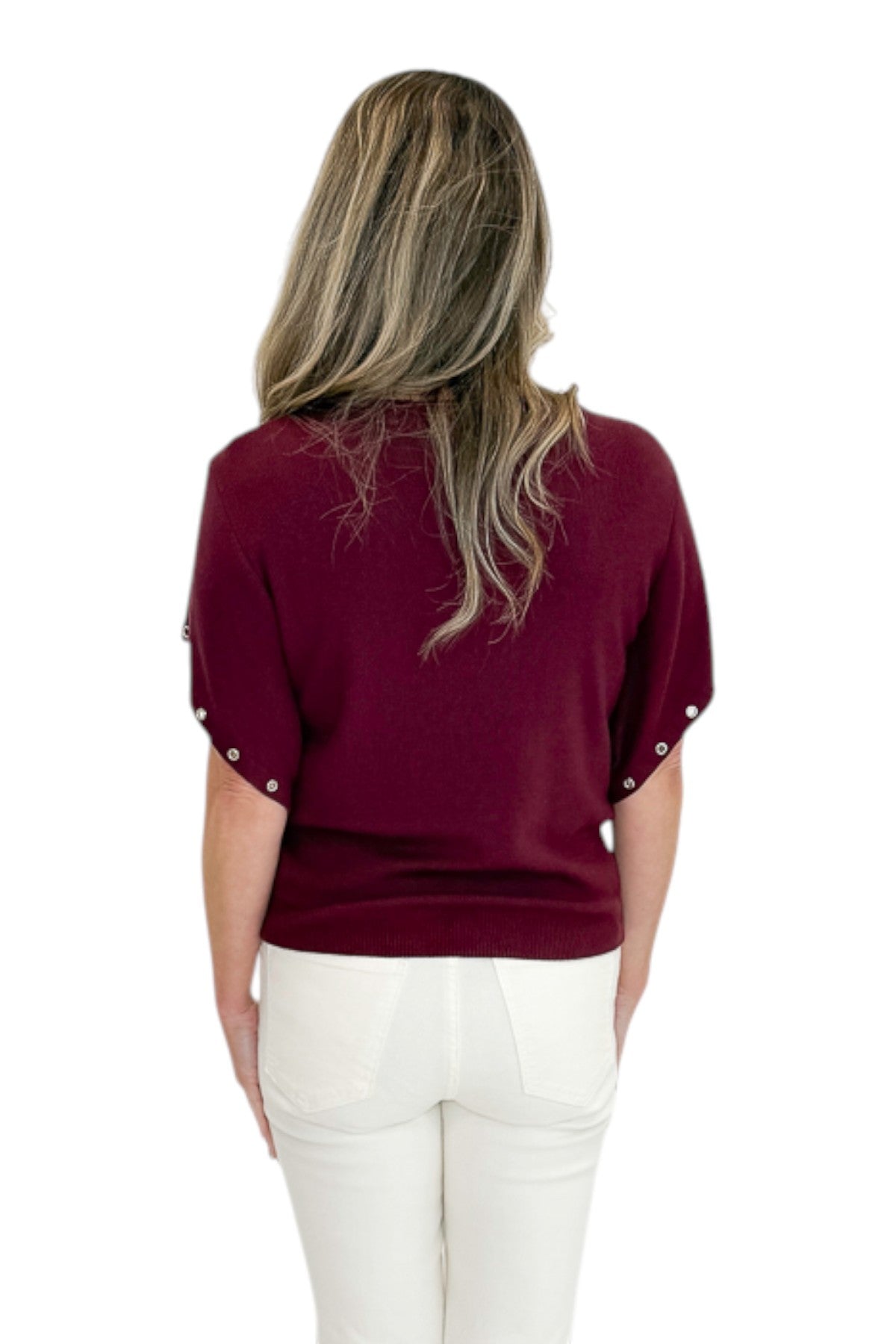 Back view of woman wearing Swagger Boutique’s Wine Grommet Sleeve Knit Top by Entro with jeans against white studio background.