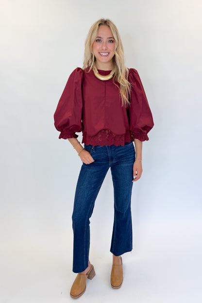 Front view of woman wearing Swagger Boutique’s Wine Lace Trim Top by Entro with jeans against white studio background.