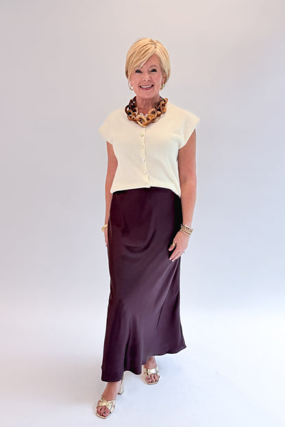 Front view of woman wearing Swagger Boutique’s Wine Satin Maxi Skirt with sweater against white studio background.
