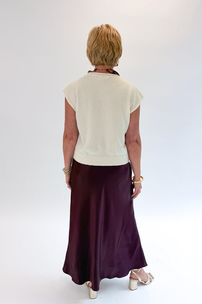 Back view of woman wearing Swagger Boutique’s Wine Satin Maxi Skirt with sweater against white studio background.