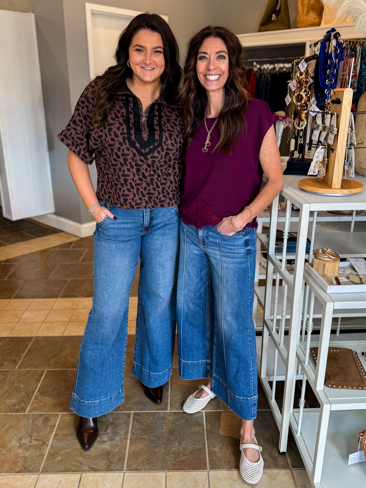 Front view of women wearing Swagger Boutique’s Leopard Half Zip Top by Entro with jeans and Wine Short Sleeve Lace Trim Top standing at the store.