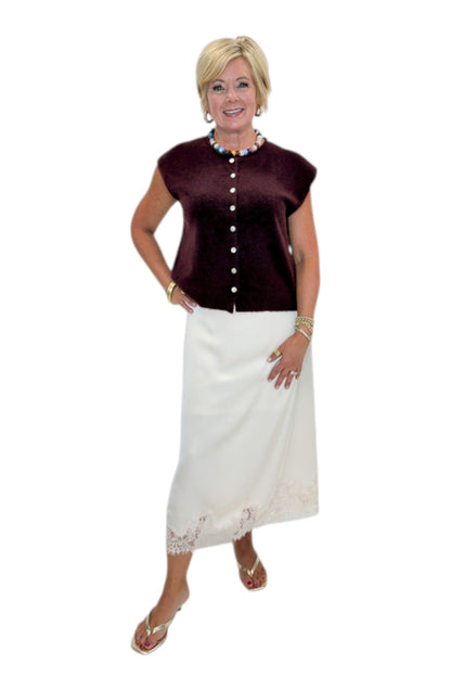Front view of woman wearing Swagger Boutique’s Wine Sleeveless Button Up Sweater with Ecru Lace Lined Satin Skirt by Entro against white studio background.