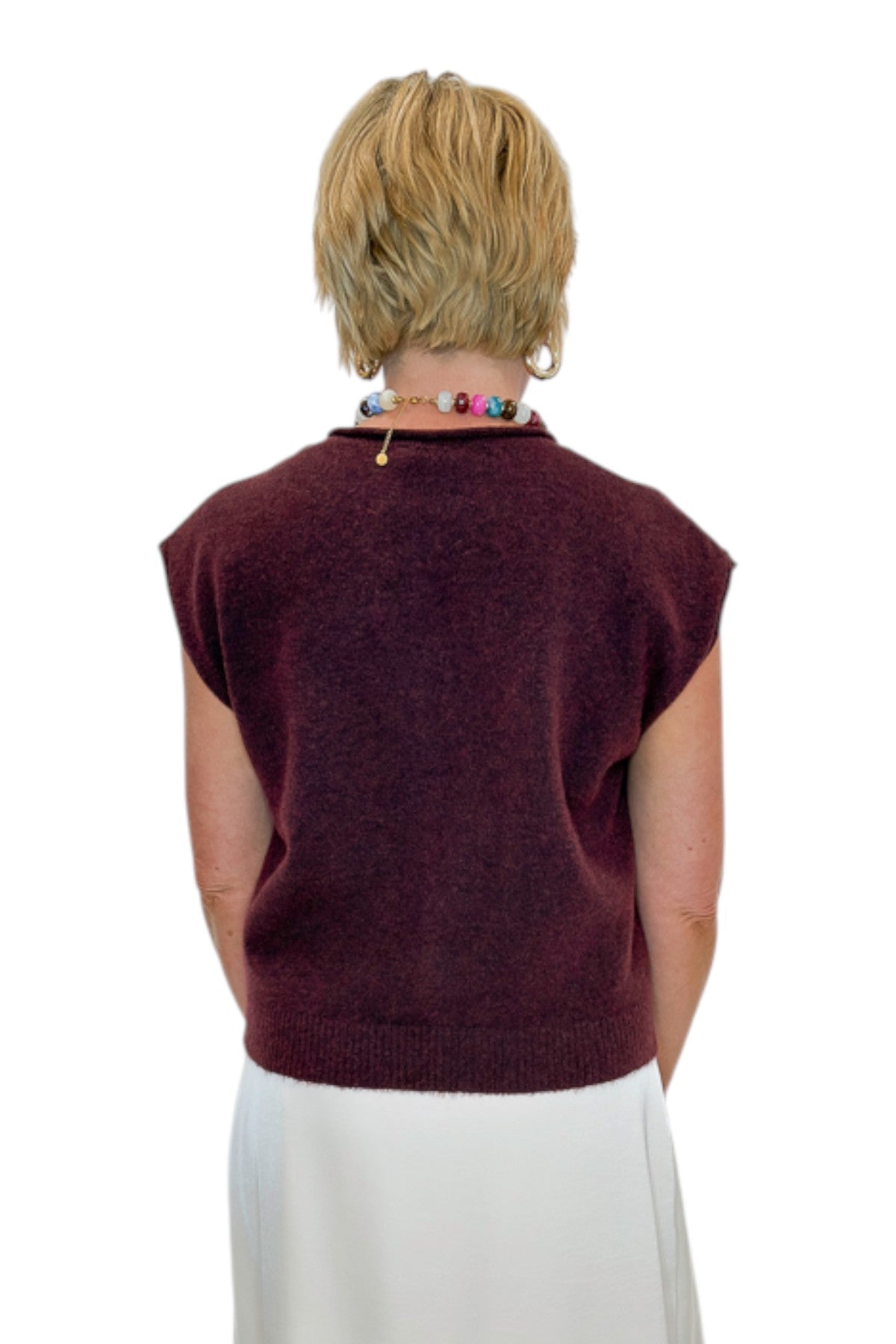 Back view of woman wearing Swagger Boutique’s Wine Sleeveless Button Up Sweater with Ecru Lace Lined Satin Skirt by Entro against white studio background.