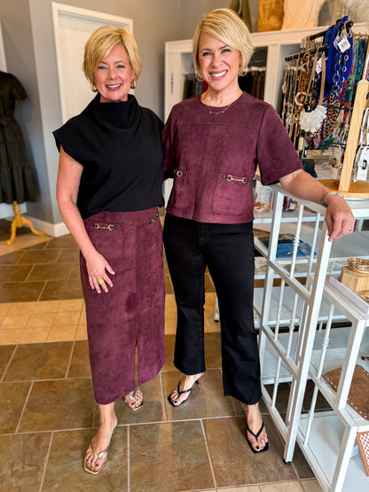Front view of women wearing Swagger Boutique’s Merlot Suede Horsebit Pocket Top Skirt by Entro &amp; black sweater and Merlot Suede Horsebit Pocket Top by Entro with jeans standing at the store together.