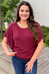 Front view of woman wearing Swagger Boutique’s Wine Grommet Sleeve Knit Top by Entro with jeans standing outside.