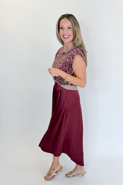 Side view of woman wearing Swagger Boutique’s Wine &amp; Leopard Layered Midi Dress with heels against white studio background.