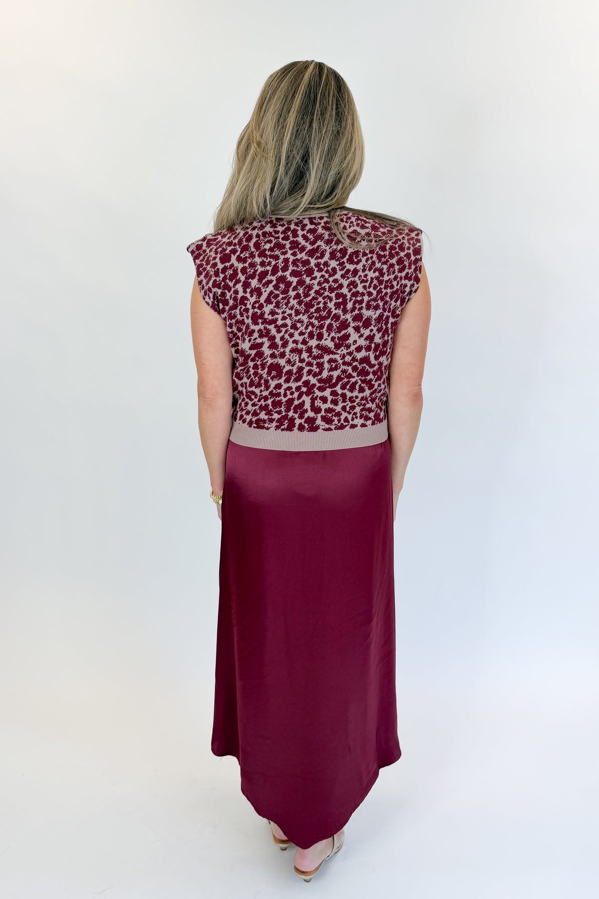 Back view of woman wearing Swagger Boutique’s Wine &amp; Leopard Layered Midi Dress with heels against white studio background.