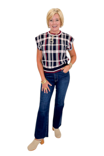 Front view of woman wearing Swagger Boutique’s Wine &amp; Navy Plaid Sleeveless Sweater by THML with jeans against white studio background.