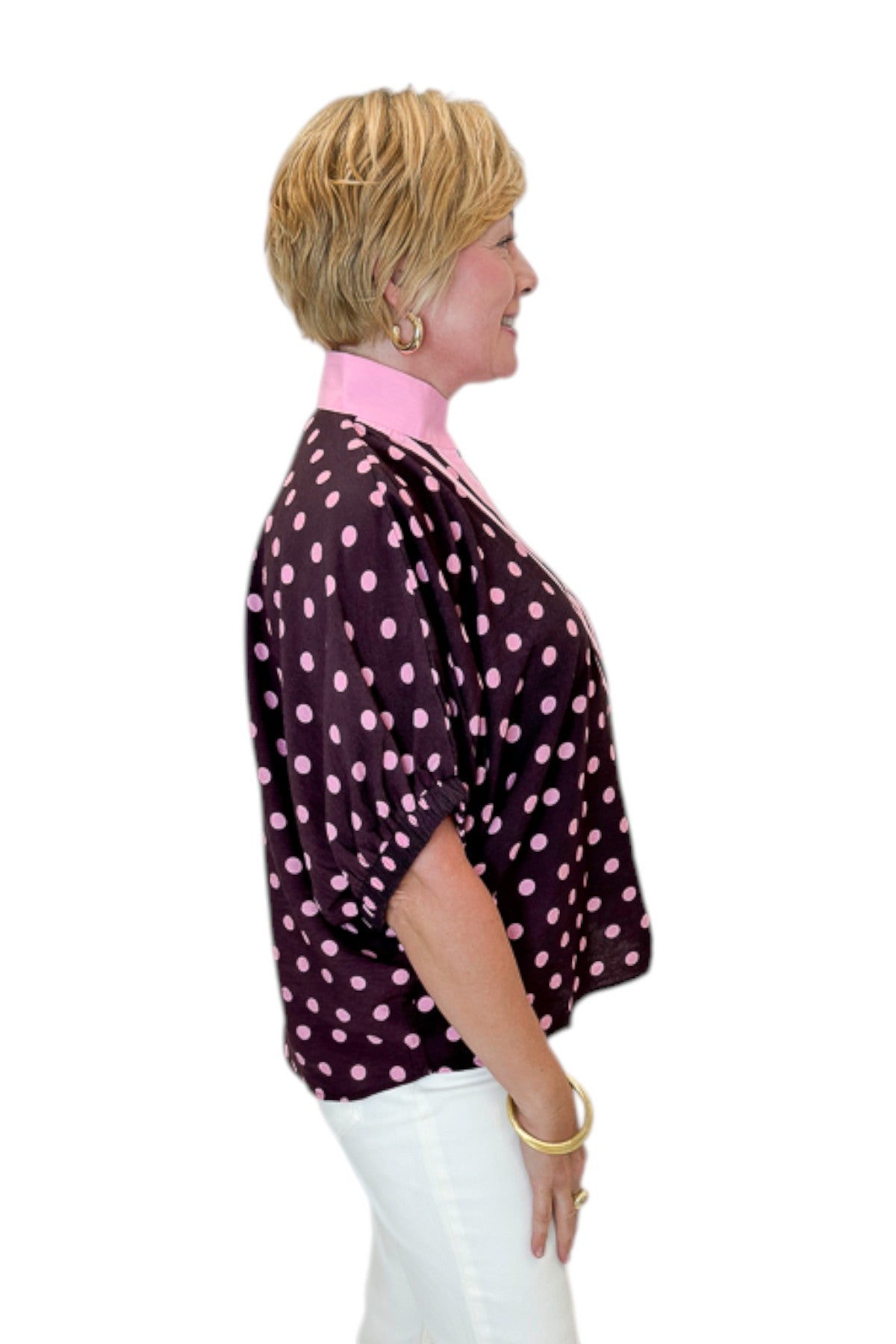 Side view of woman wearing Swagger Boutique’s Wine &amp; Pink Polka Dot Dolman Sleeve Top by Entro with jeans against white studio background.