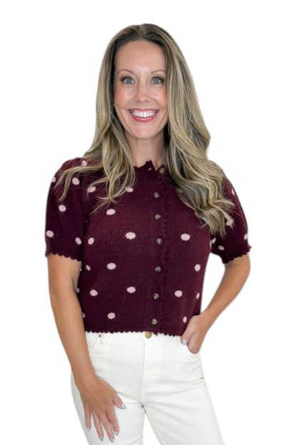 Front view of woman wearing Swagger Boutique’s Wine &amp; Pink Polka Dot Short Sleeve Cardigan by Entro with jeans against white studio background.