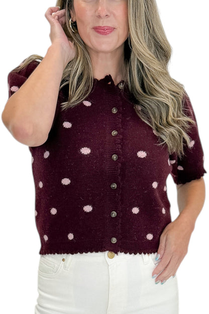 Front detail view of woman wearing Swagger Boutique’s Wine &amp; Pink Polka Dot Short Sleeve Cardigan by Entro with jeans against white studio background.