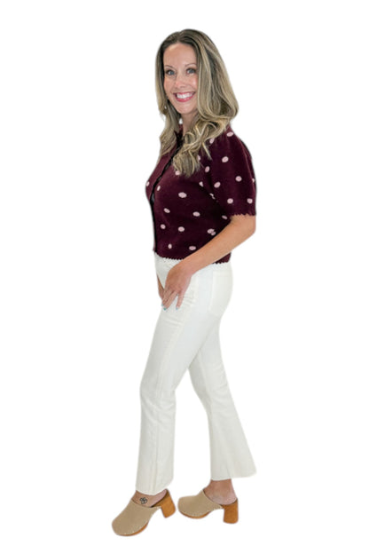 Side view of woman wearing Swagger Boutique’s Wine &amp; Pink Polka Dot Short Sleeve Cardigan by Entro with jeans against white studio background.