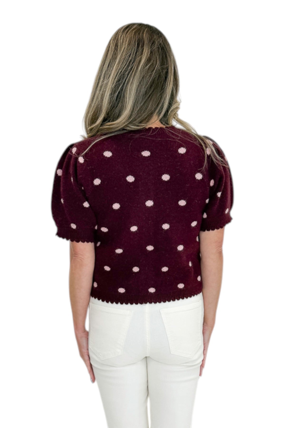 Back view of woman wearing Swagger Boutique’s Wine &amp; Pink Polka Dot Short Sleeve Cardigan by Entro with jeans against white studio background.