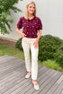 Front view of woman wearing Swagger Boutique’s Wine & Pink Polka Dot Short Sleeve Cardigan by Entro with jeans  standing outside on a deck.