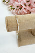 Pearl bracelet on a roll of burlap with pink flowers in the background