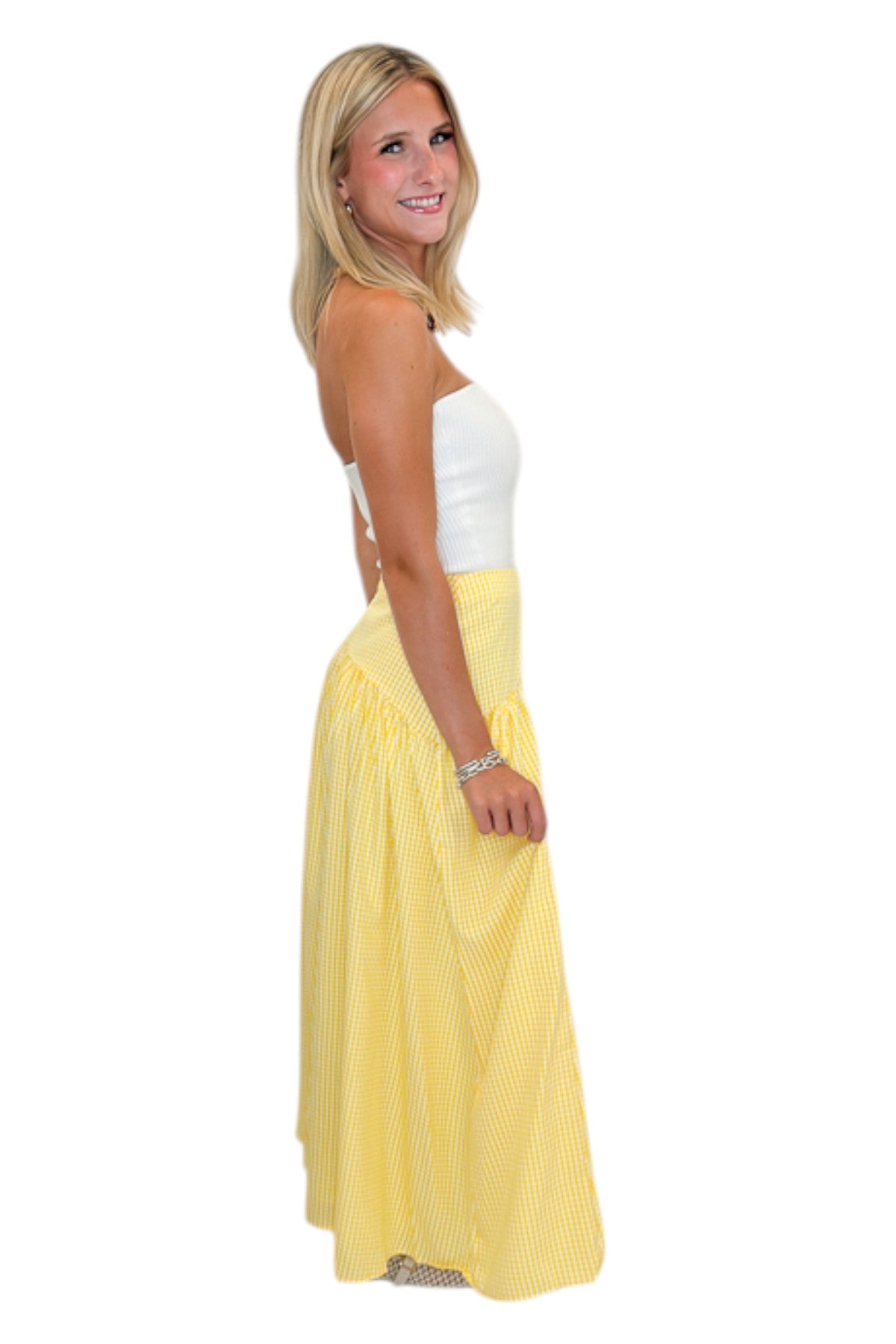 Side view of woman wearing Swagger Boutique’s Yellow Gingham Skirt with white top against white studio background.