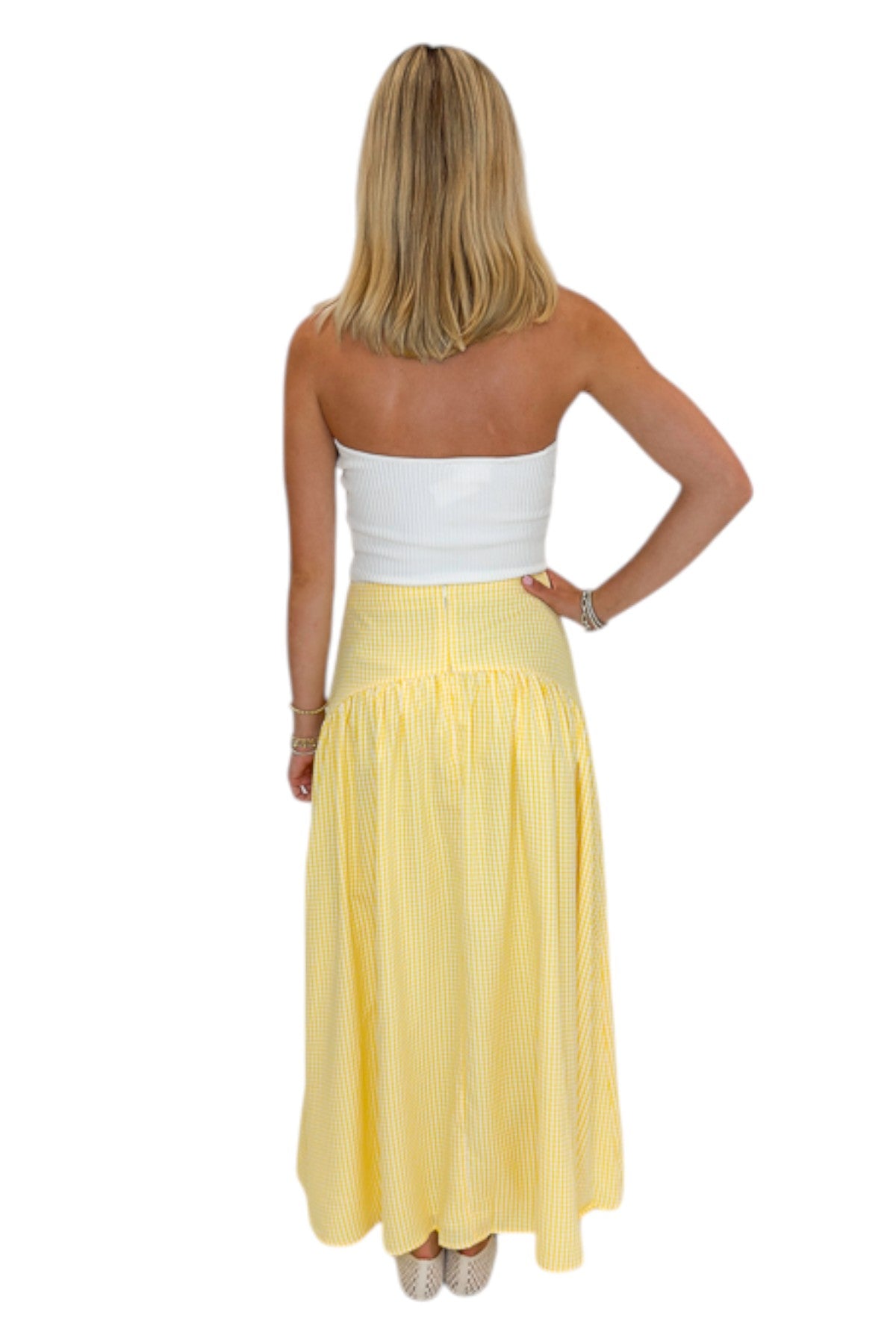 Back view of woman wearing Swagger Boutique’s Yellow Gingham Skirt with white top against white studio background.