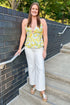 Front view of woman wearing Swagger Boutique’s Yellow Lemon Cut Out Tank with jeans standing outside.
