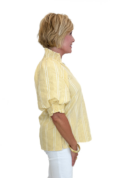Side view of woman wearing Swagger Boutique’s Yellow Striped Puff Sleeve Top with jeans against white studio background.