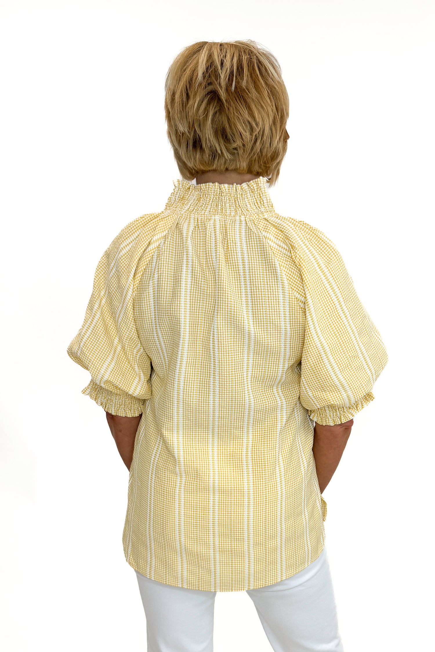 Back view of woman wearing Swagger Boutique’s Yellow Striped Puff Sleeve Top with jeans against white studio background.