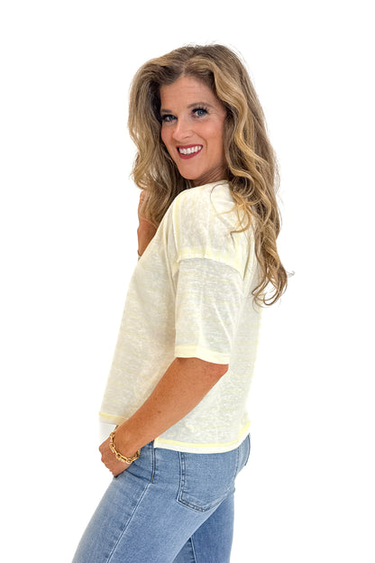 Side view of woman wearing Swagger Boutique’s Yellow Striped Relaxed Fit Top with jeans against white studio background.