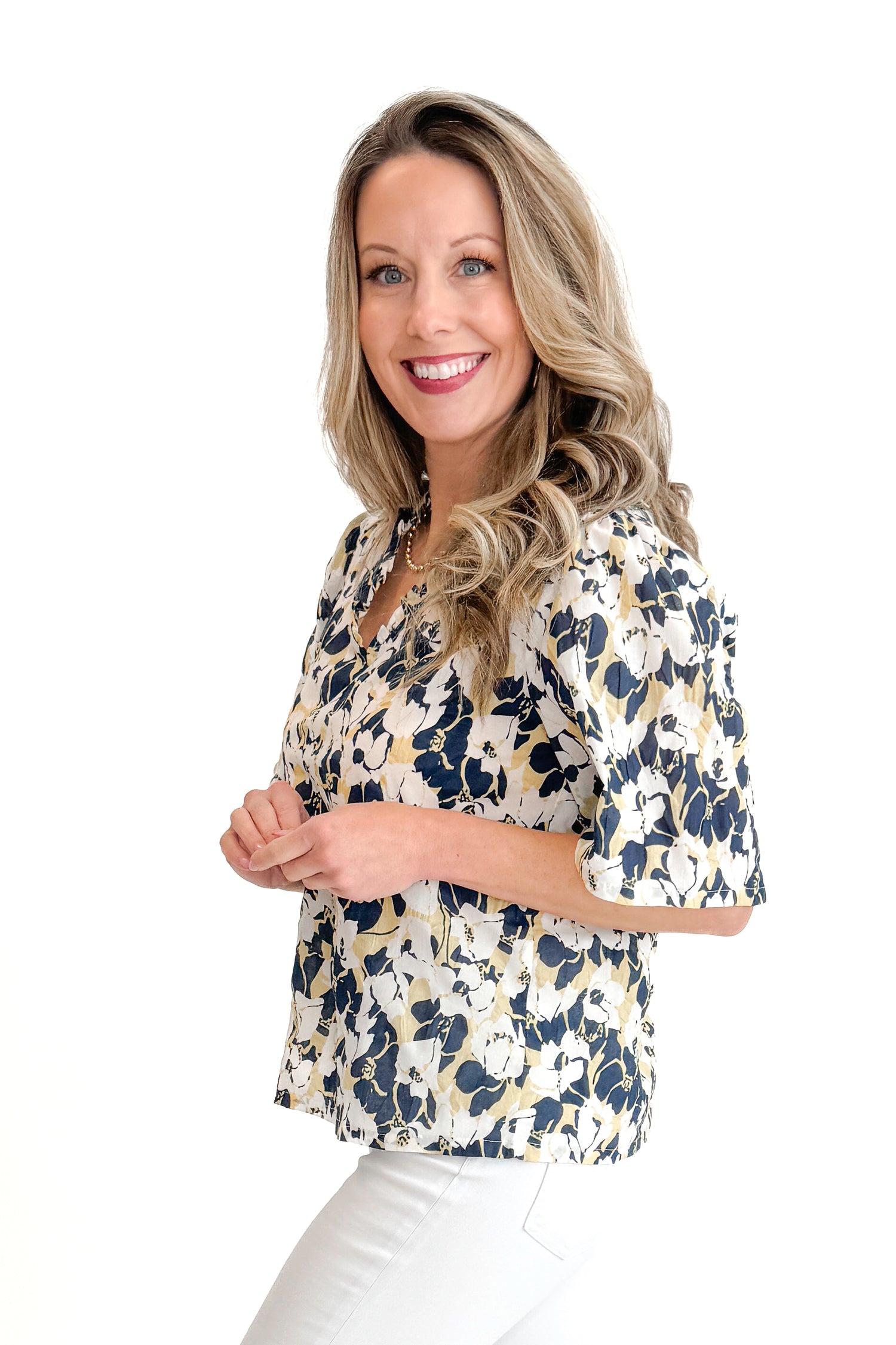 Side view of woman wearing Swagger Boutique’s Yellow &amp; Navy Floral Printed Top with jeans against white studio background.
