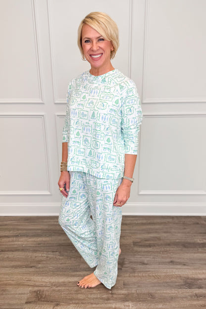Side view of the Yueltide Vignettes Blue Annie Pajama Set, featuring a soft blue and green holiday print with Christmas trees, wreaths, and festive details. The relaxed long-sleeve top pairs with matching straight-leg pajama pants featuring convenient side pockets.