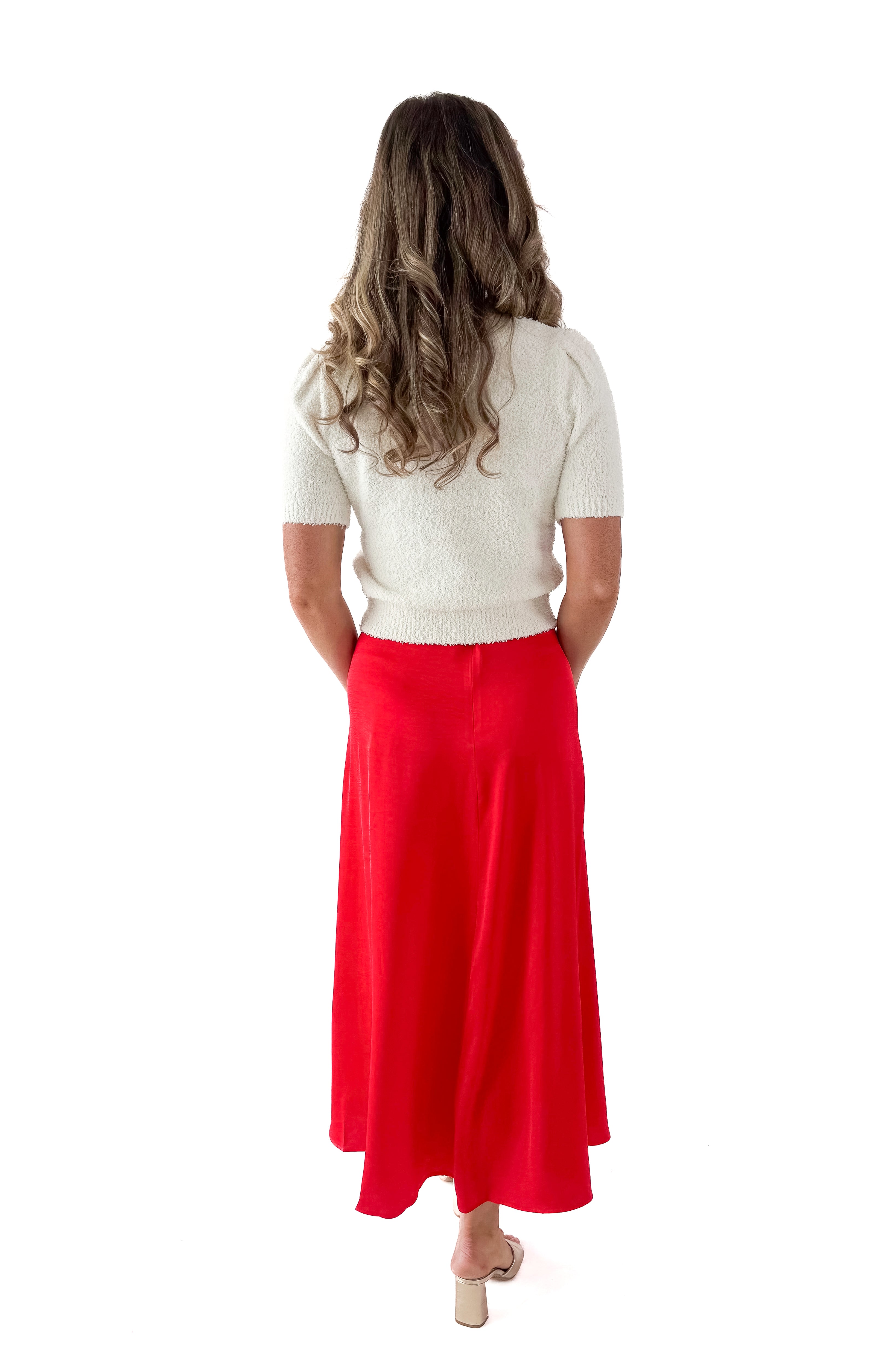Back view of woman wearing cream top with Festive Red Northpointe Midi Skirt against white studio background.