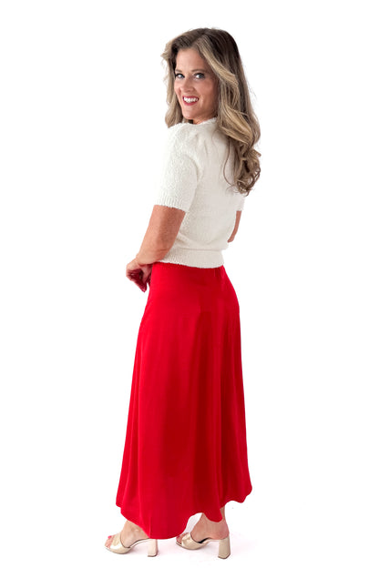 Side view of woman wearing cream top with Festive Red Northpointe Midi Skirt against white studio background.
