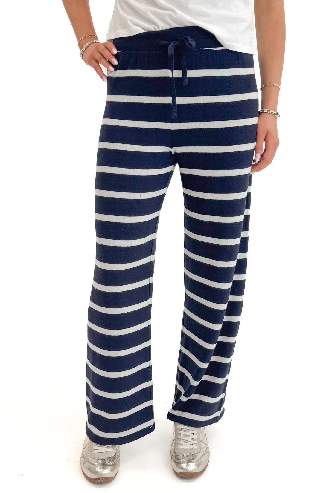 Front detail view of woman wearing Eclipse Overboard Stripe Pant by Z Supply with white top against white studio background.