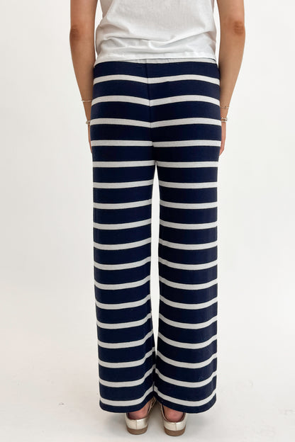 Back detail view of woman wearing Eclipse Overboard Stripe Pant by Z Supply with white top against white studio background.