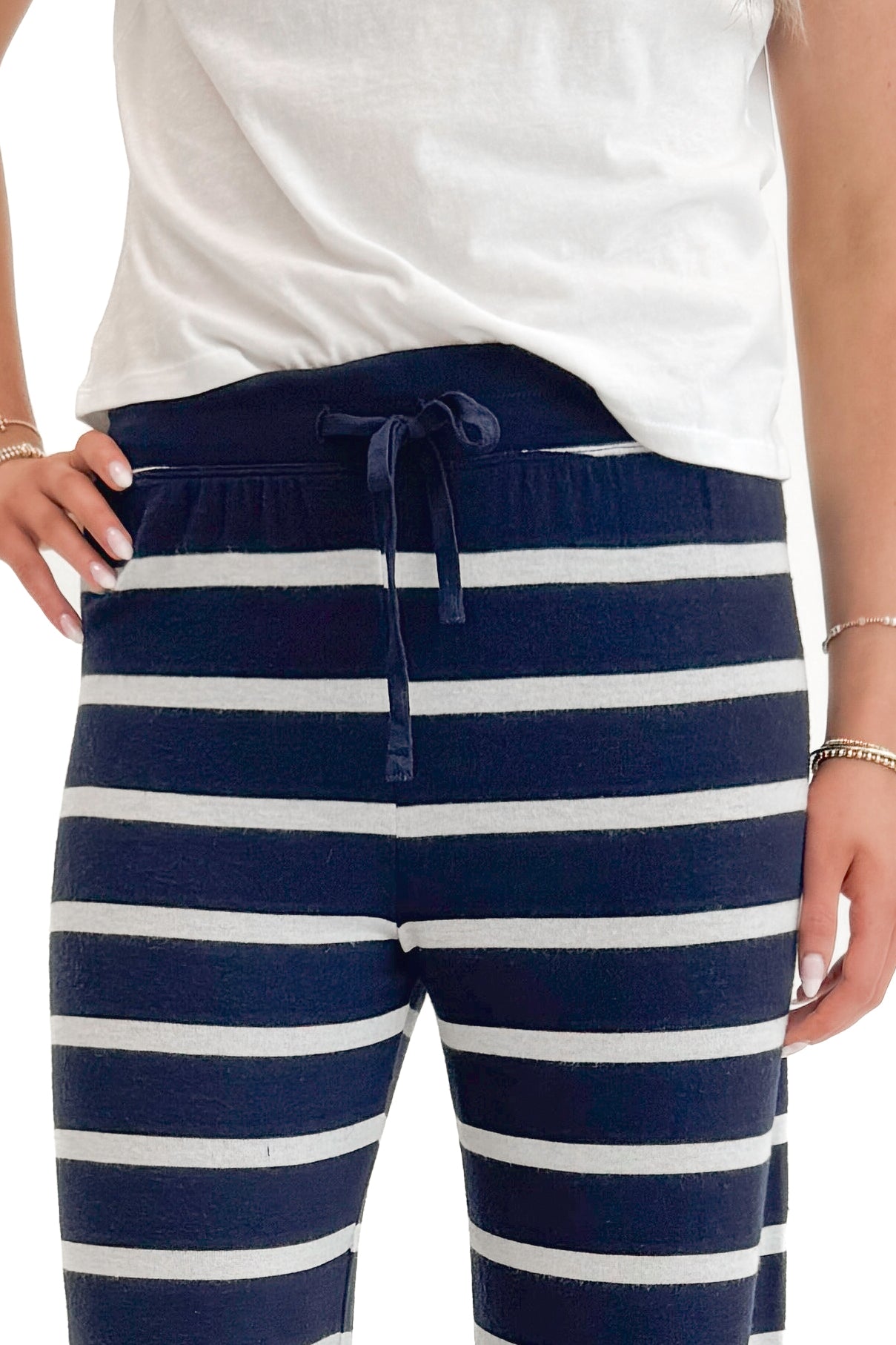 Front detail view of woman wearing Eclipse Overboard Stripe Pant by Z Supply with white top against white studio background.