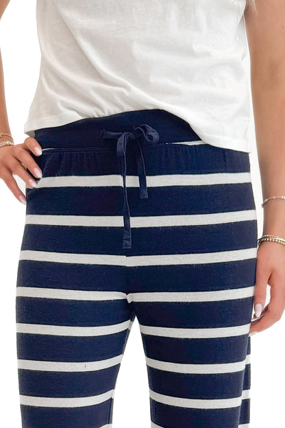Front detail view of woman wearing Eclipse Overboard Stripe Pant by Z Supply with white top against white studio background.