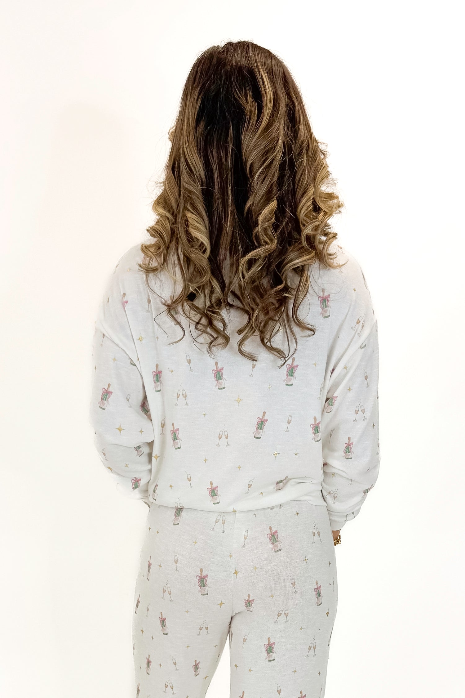 Back view of woman wearing Vanilla Ice Champagne Long Sleeve Top with matching pants against white studio background.