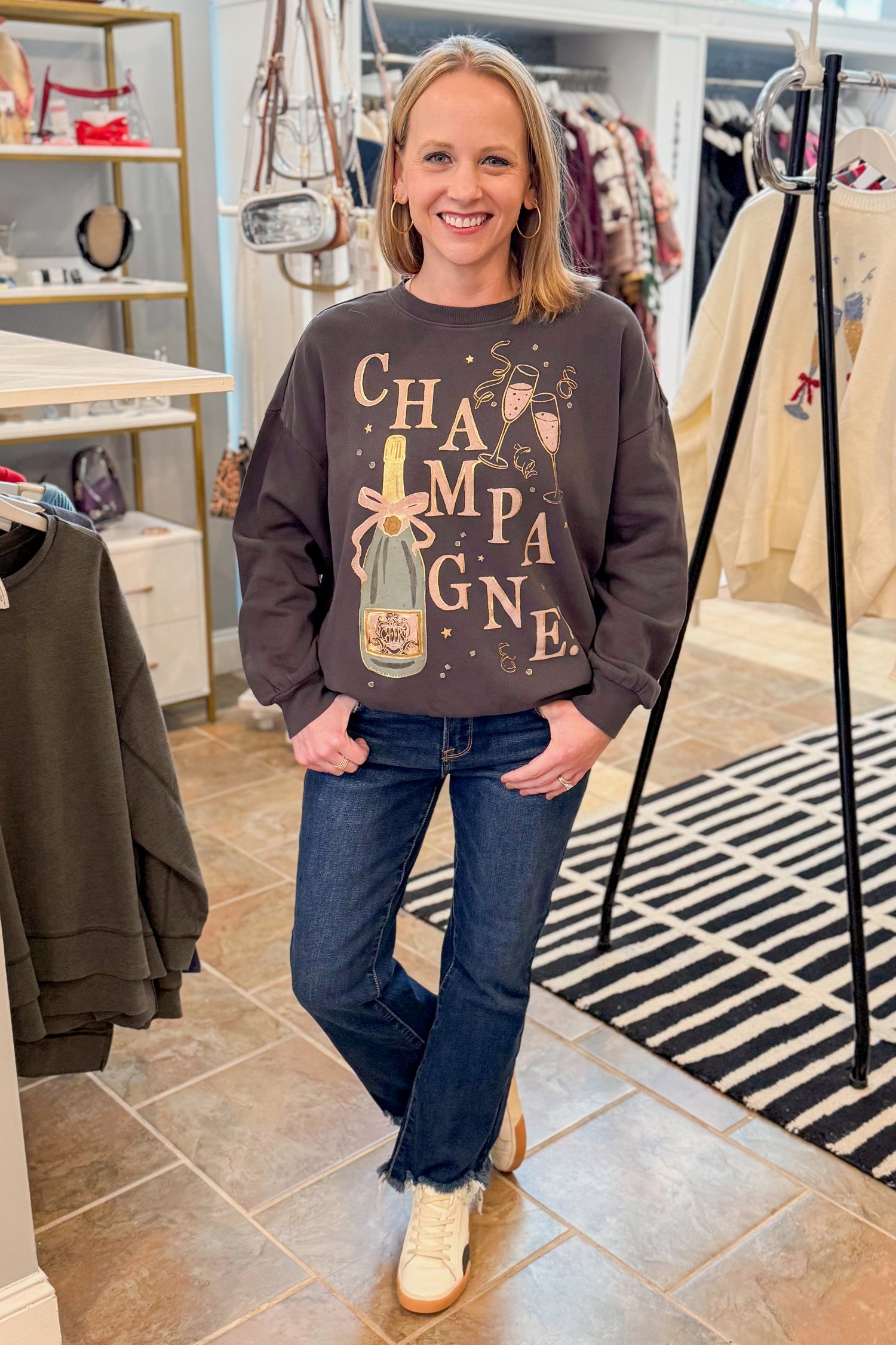 Front view of woman wearing Black Celebrate Sunday Sweatshirt with jeans at a boutique.