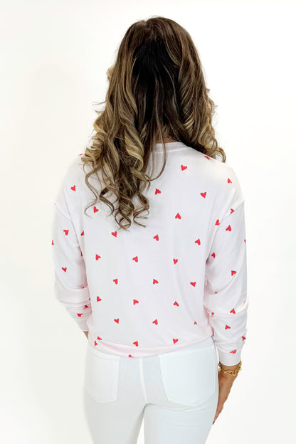 Back view of woman wearing Pink Marshmallow Mira Heart Top with jeans against white studio background.