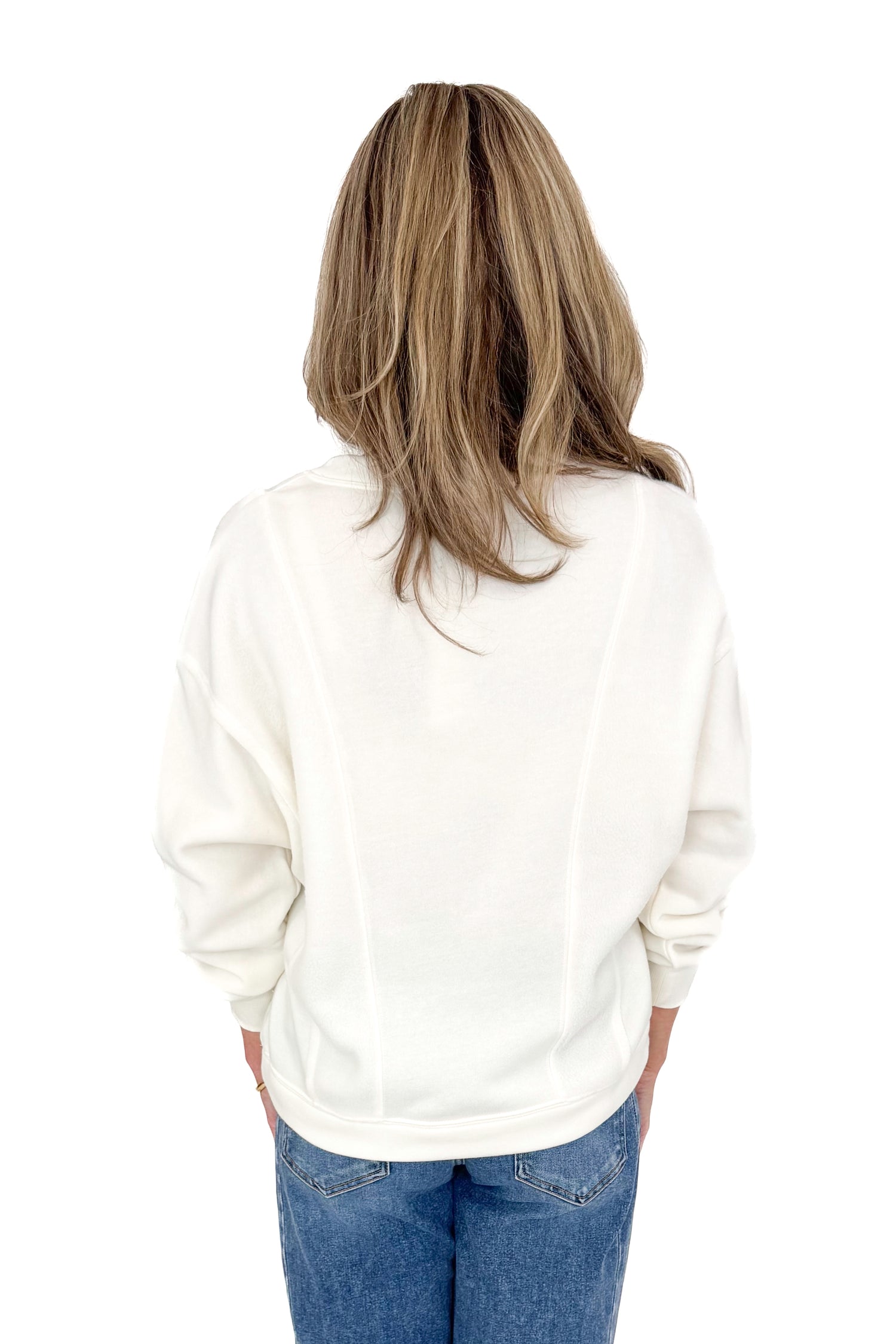 Back view of woman wearing Z Supply cream top with jeans against white studio background.