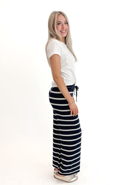 Side view of woman wearing White Junie Tee Shirt by Z Supply with pants against white studio background.
