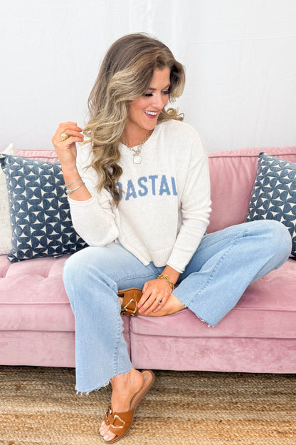Front view of woman wearing Light Heather Oatmeal Sienna Coastal Sweater by Z Supply with jeans sitting on a couch.