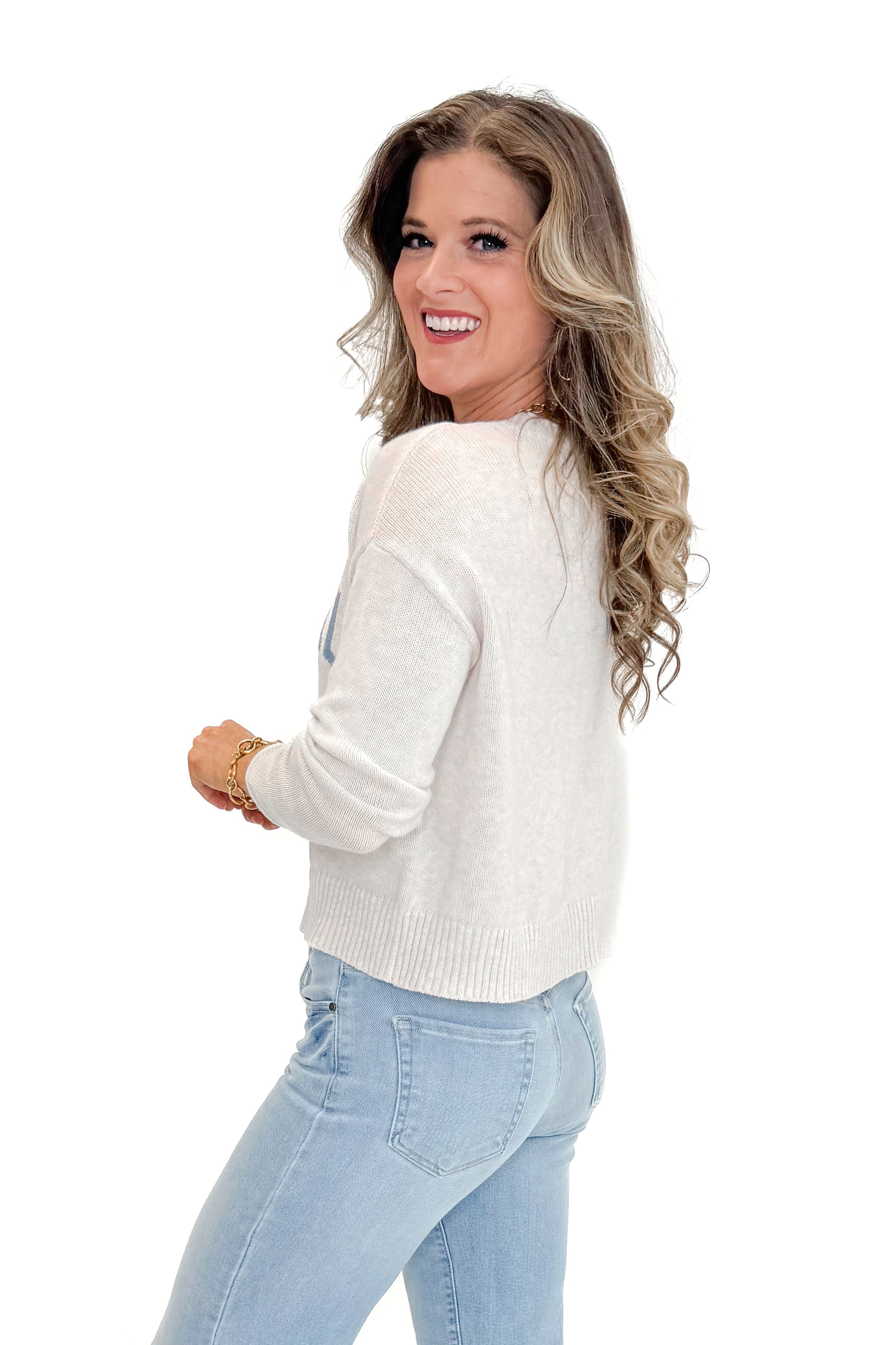 Side view of woman wearing Light Heather Oatmeal Sienna Coastal Sweater by Z Supply with jeans against white studio background.
